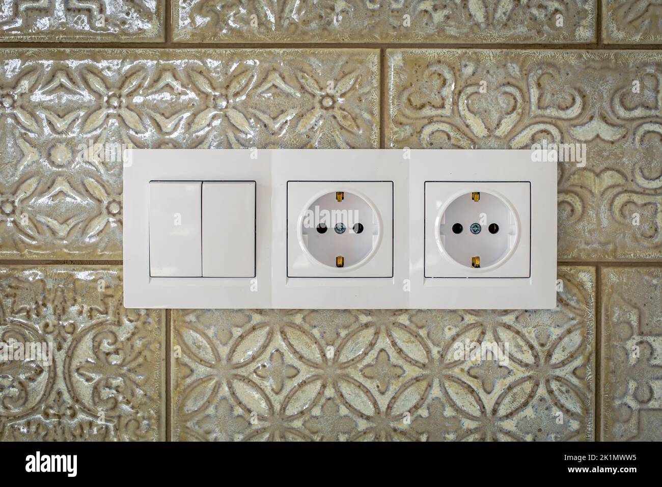 White plastic walk-through switches and sockets on a white wall. Stock Photo