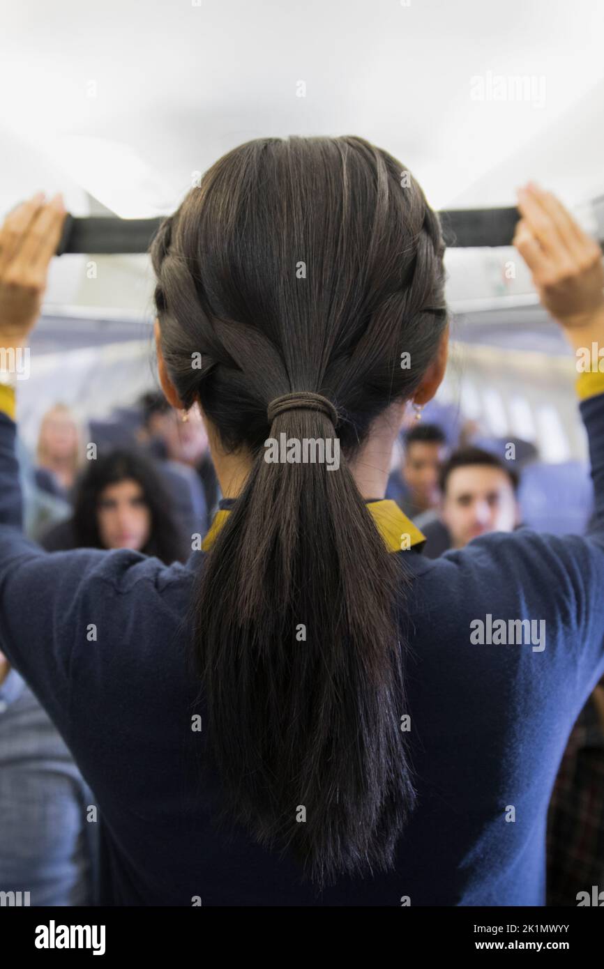 Female flight attendant demonstrating seat belt safety on airplane
