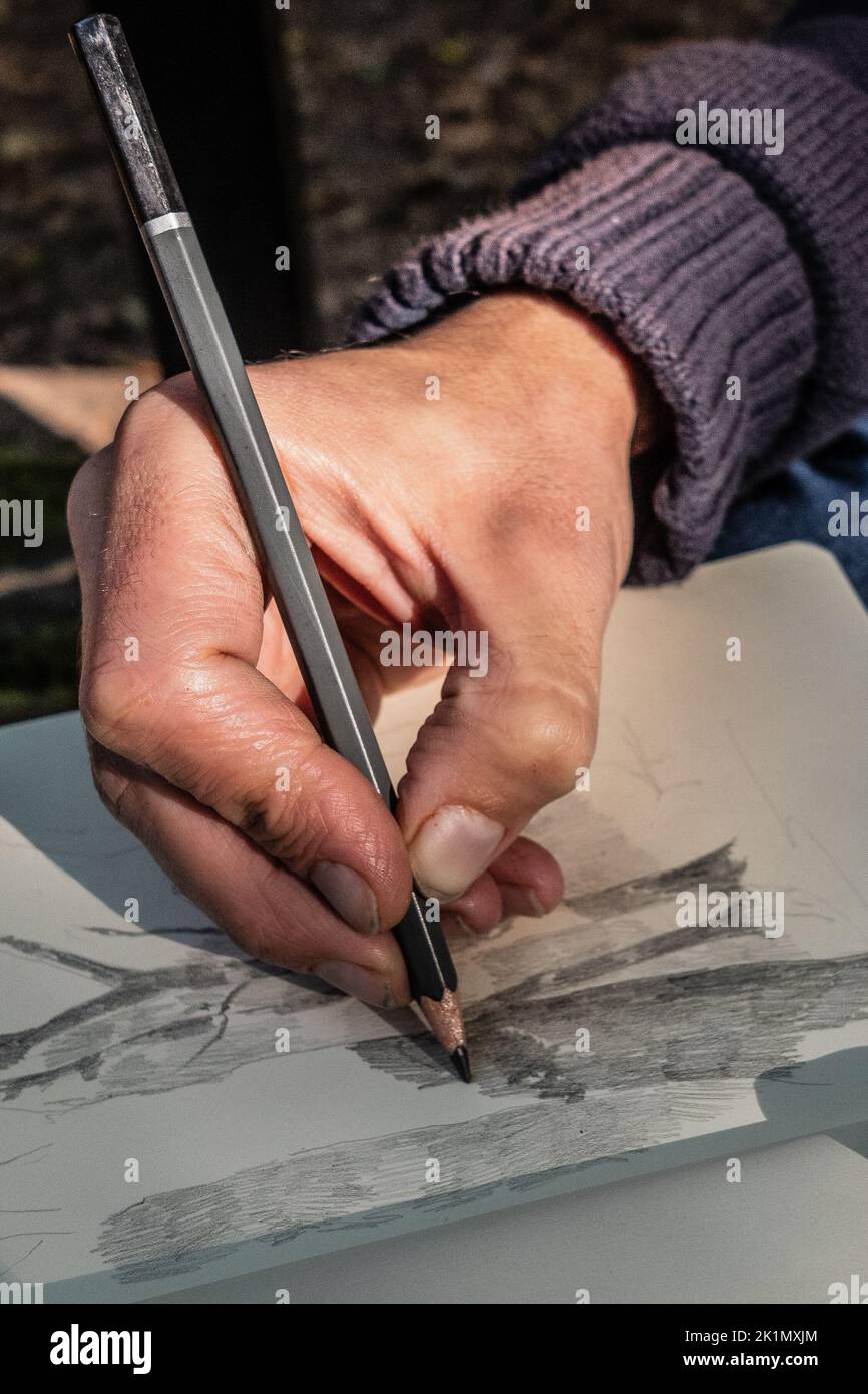 Artist's hand sketching a pencil drawing. Close-up.Skin textures. Stock Photo