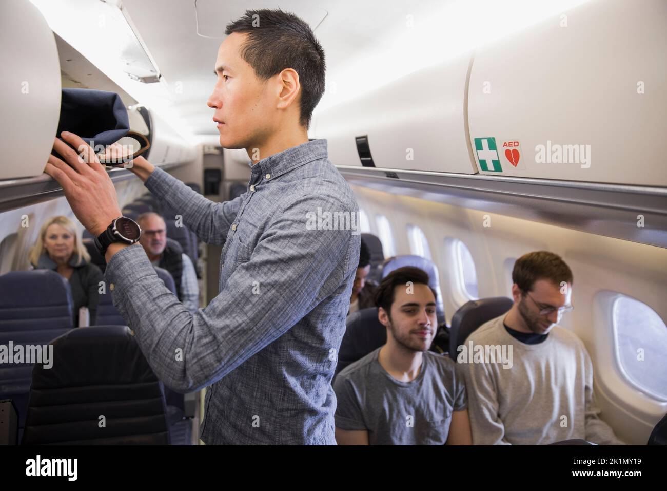 Man placing bag in airplane overhead compartment Stock Photo Alamy