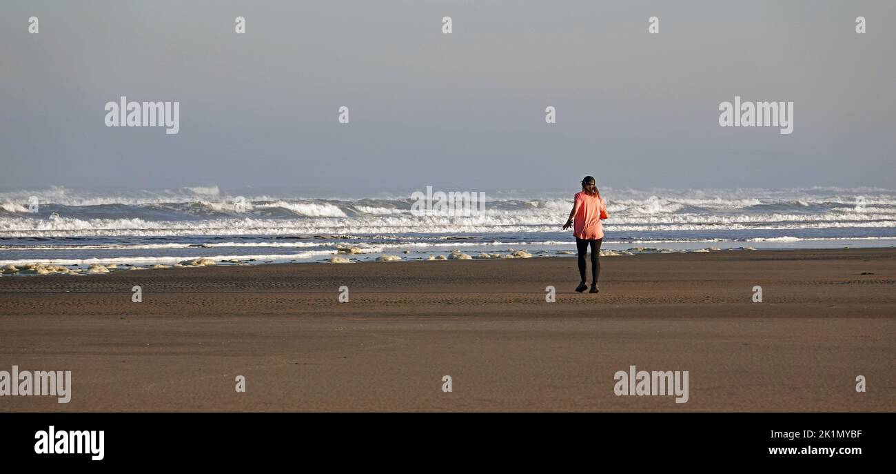 A woman taking an early morning stroll along a Pacific beach near the small town of Yachats, Oregon. Stock Photo