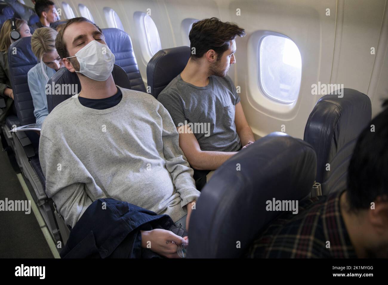 Male passenger with flu mask sleeping on airplane Stock Photo Alamy