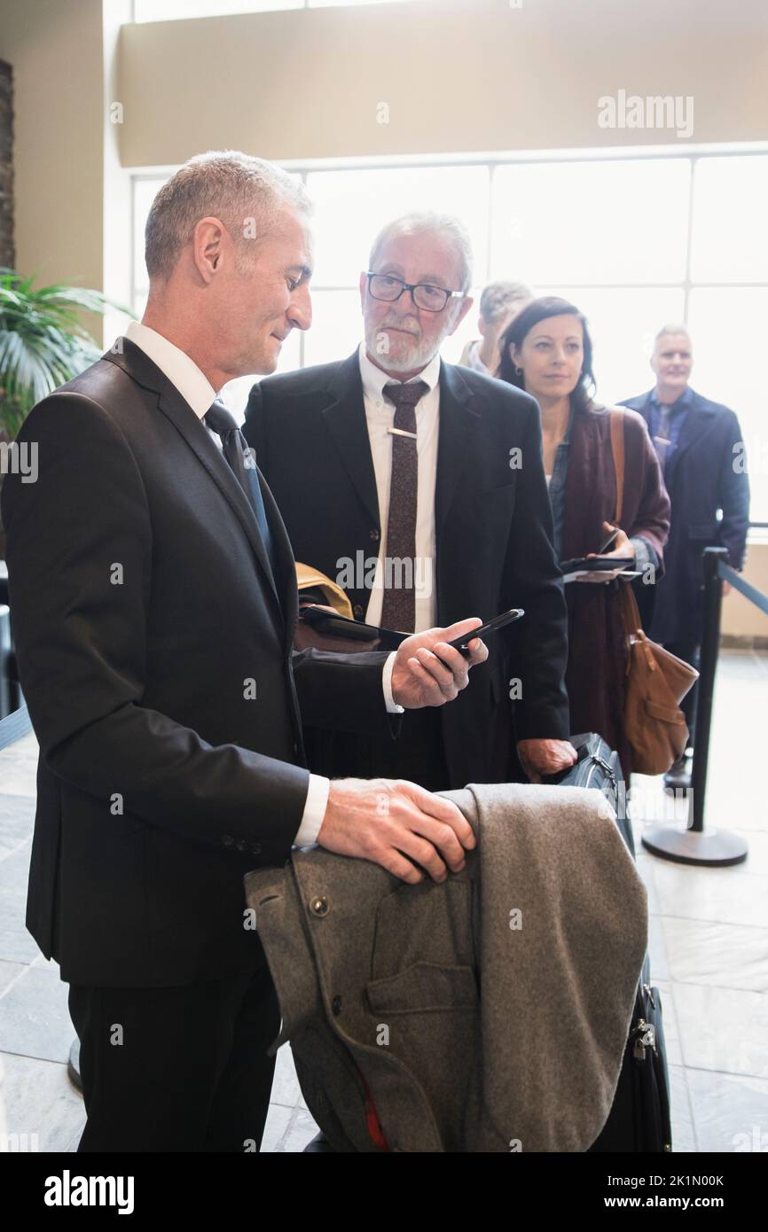 businessmen with smart phone waiting in airport queue Stock Photo
