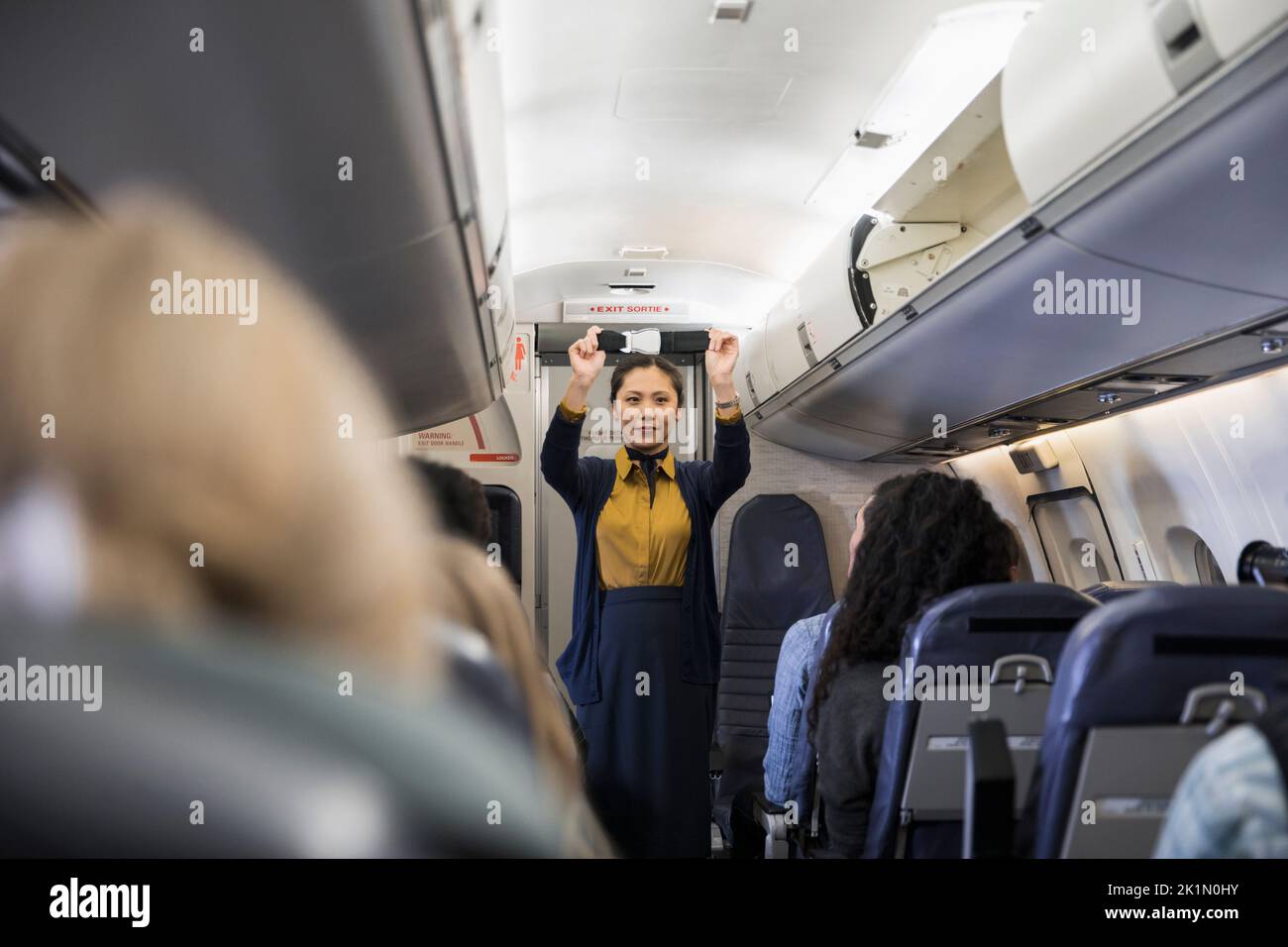 Female flight attendant demonstrating seat belt safety in airplane