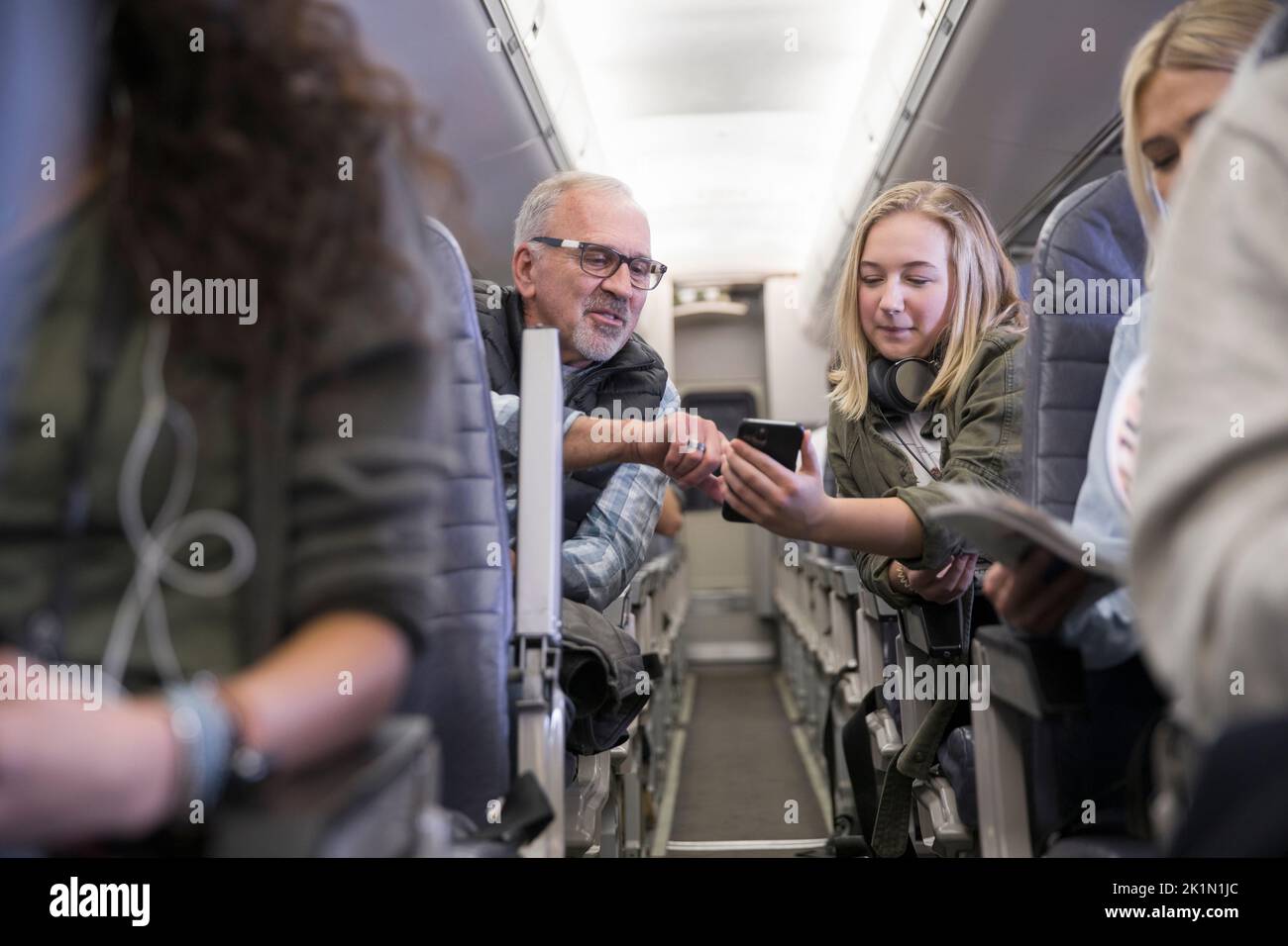 Passengers using smart phone across airplane aisle Stock Photo Alamy