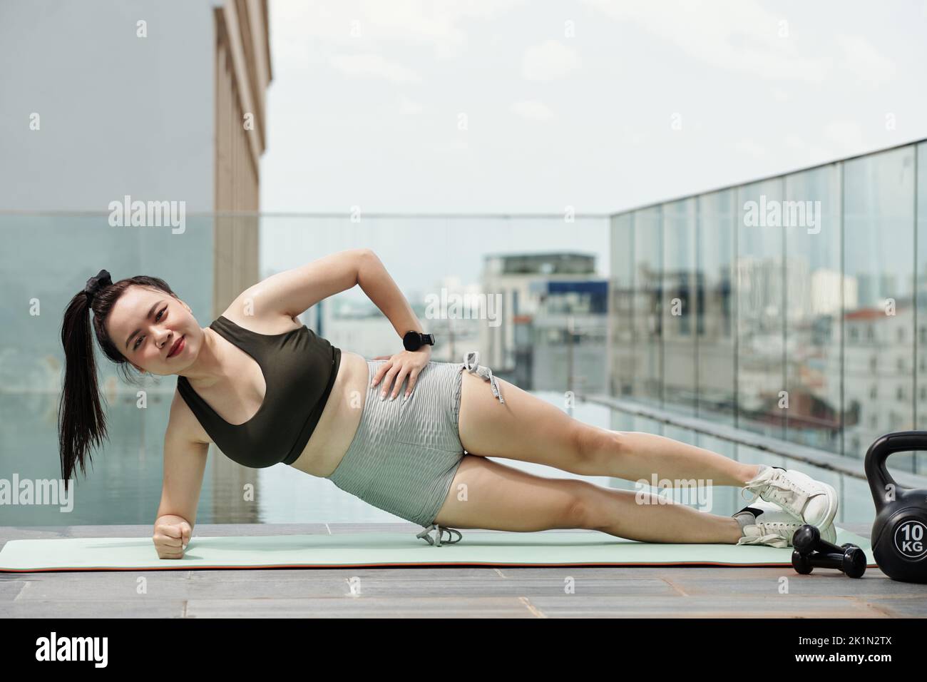 Smiling young woman doing side plank to work deep spinal stabilizing muscle Stock Photo