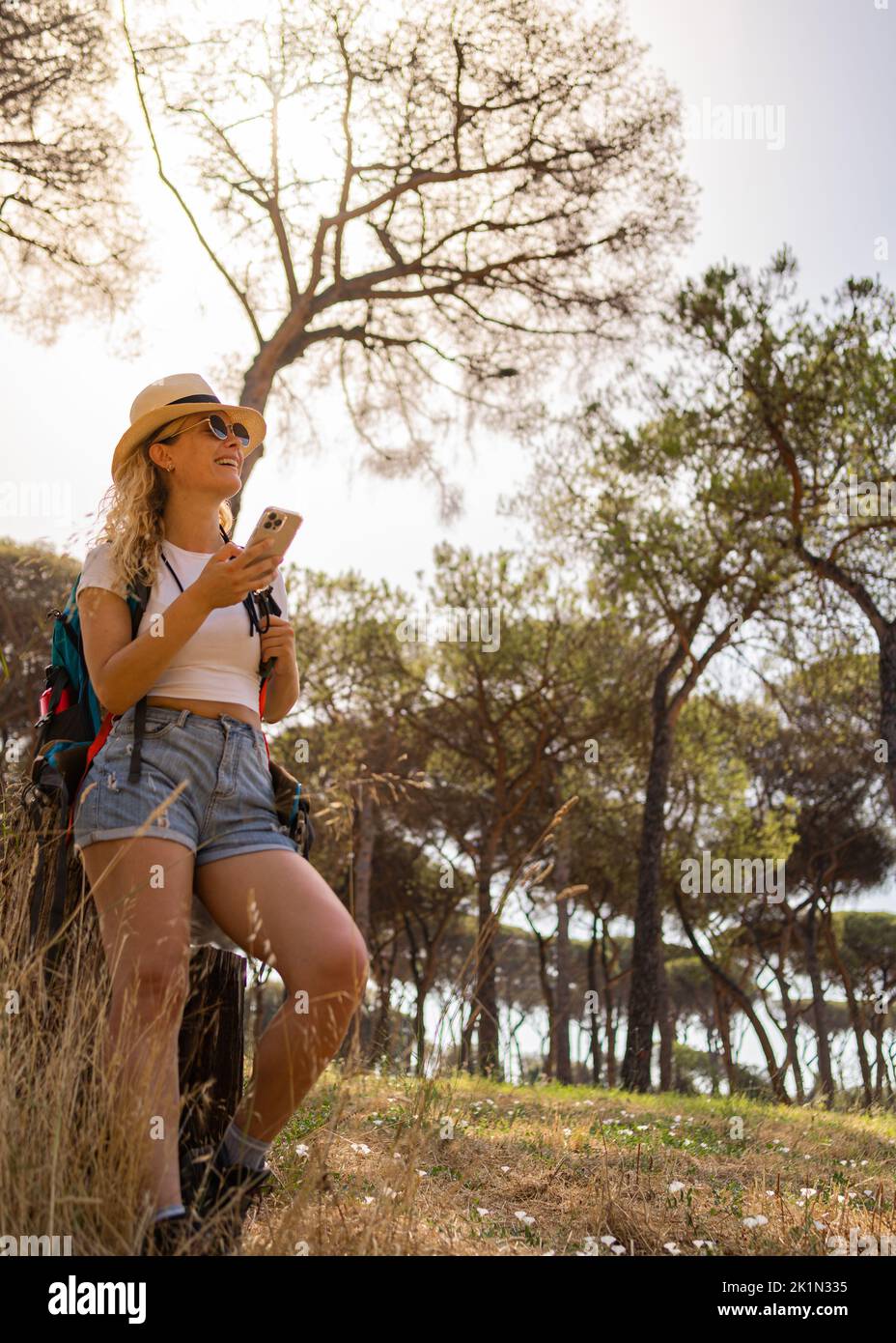 Enterprising and happy woman explores in the forest with her phone and camera, explorer woman, vertical shot Stock Photo