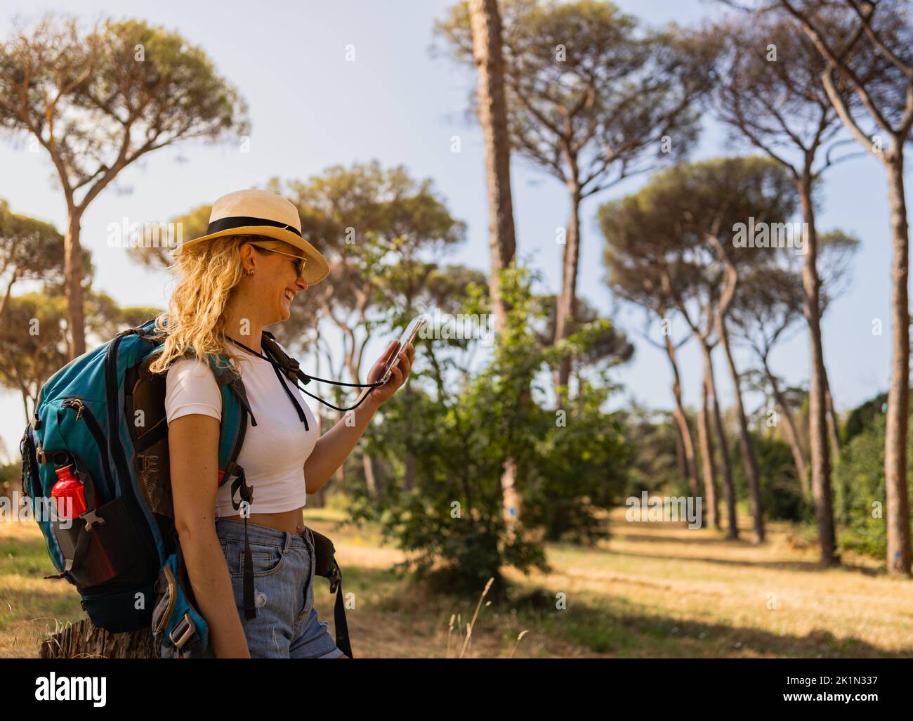 Enterprising and happy woman explores in the forest with her phone and camera, explorer woman Stock Photo