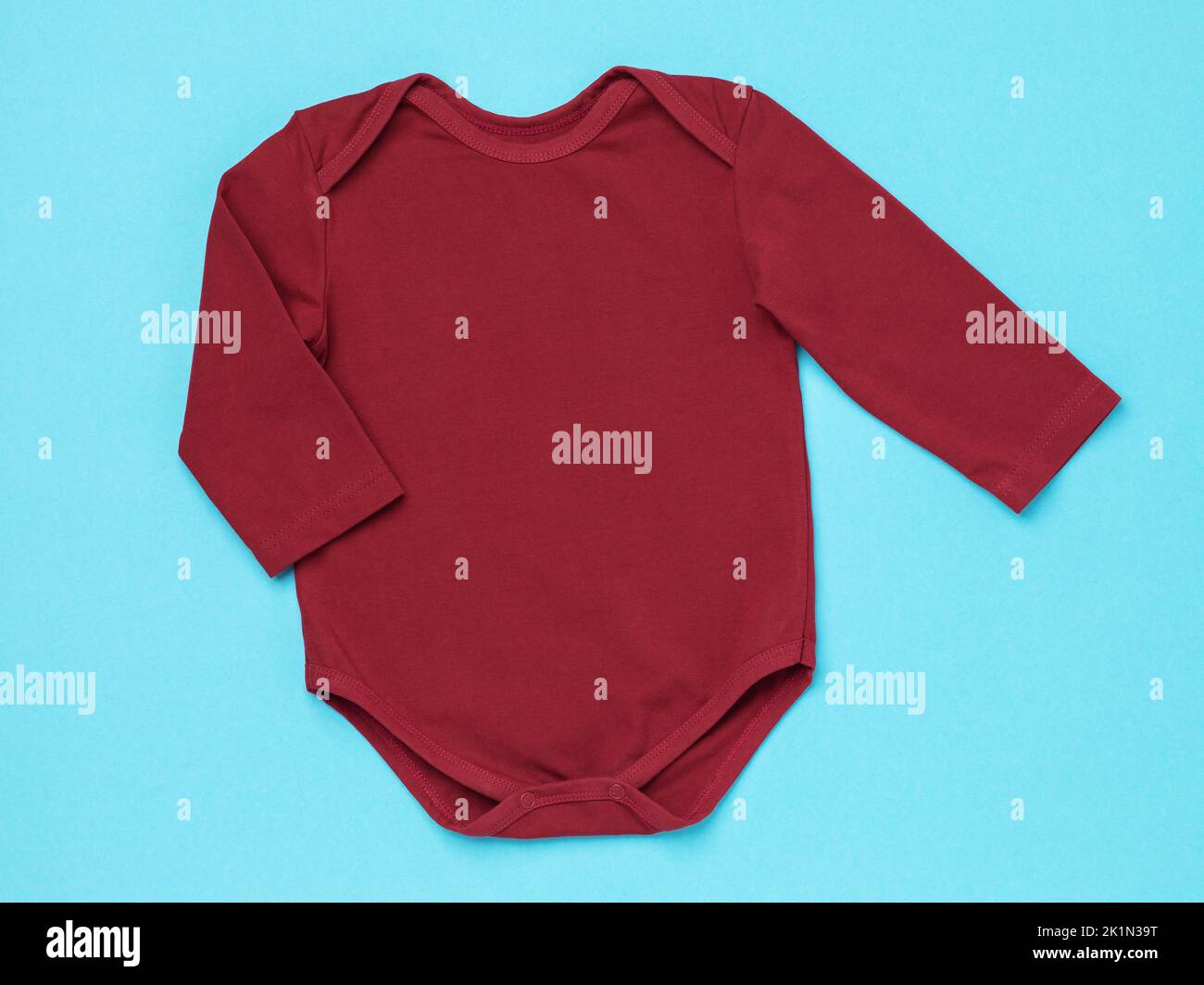 Children's bodysuit with long sleeves of burgundy color on a blue background, top view Stock Photo