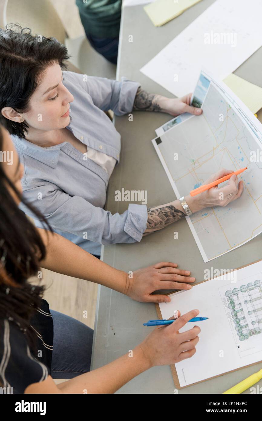 Female land use planners discussing plans in community center Stock
