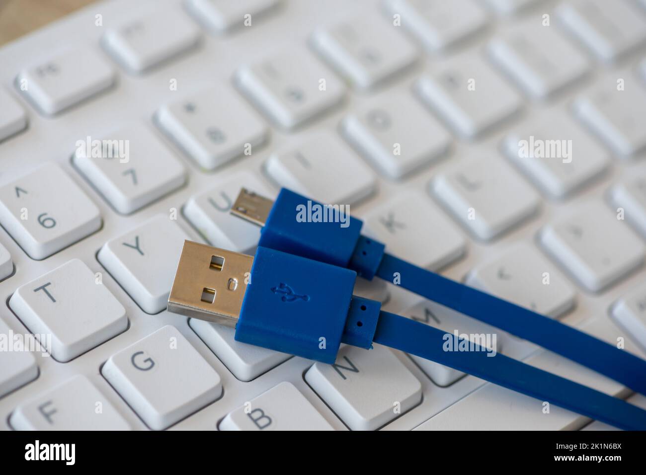 Close-up on a micro USB cable with a white keyboard in the background Stock Photo