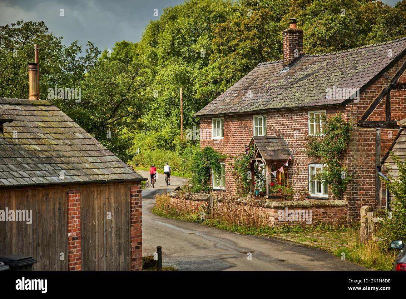 Chelford village and civil parish in Cheshire, England, countryside around the village a farm house with cyclists passing Stock Photo