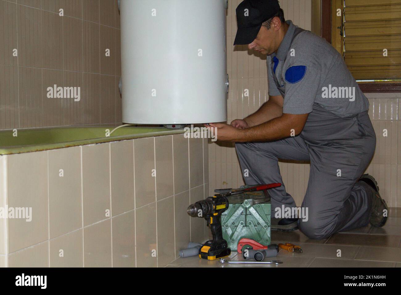Plumber in the bathroom of a house who with his work tools repairs an