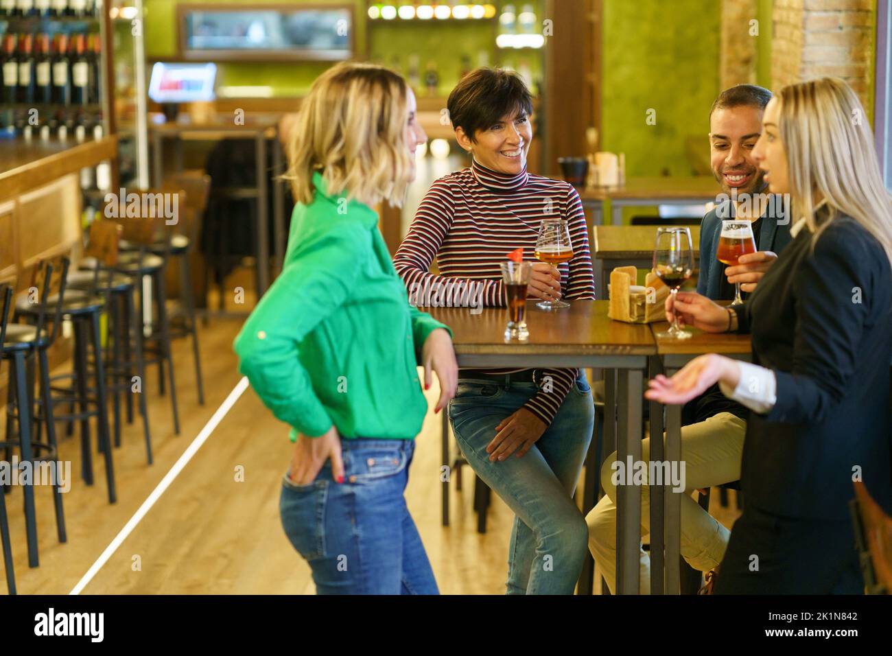 Blond woman speaking with friends in pub Stock Photo