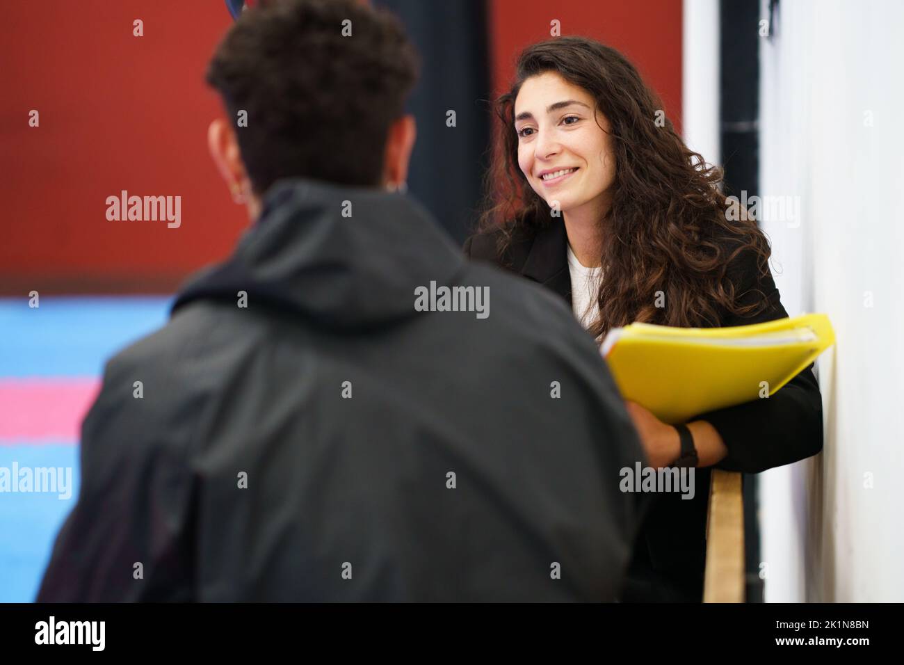 Friendly female counselor listening to sportsman in gym Stock Photo