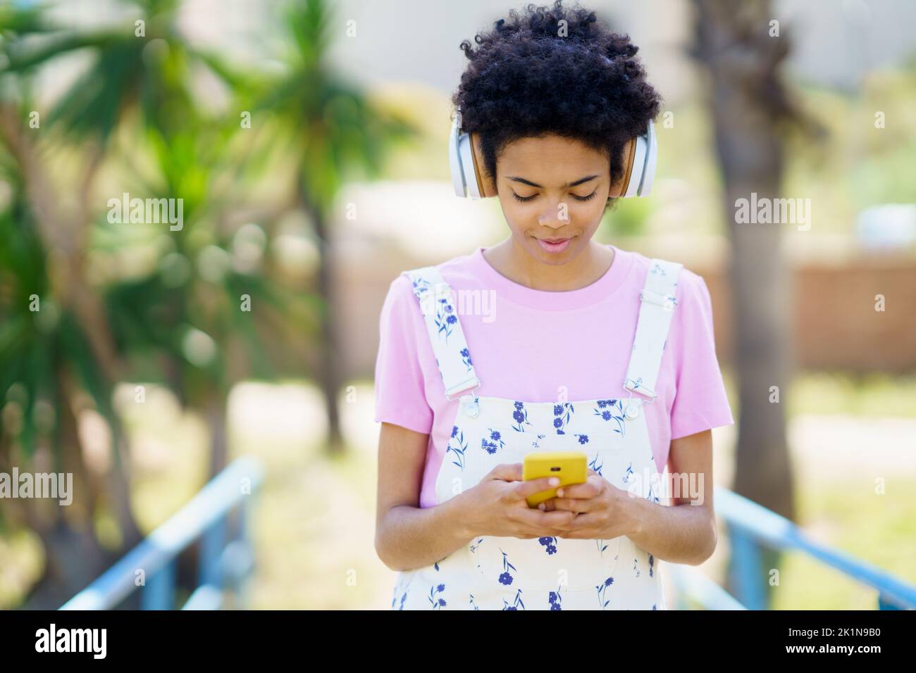 Black woman listening to music while browsing smartphone Stock Photo