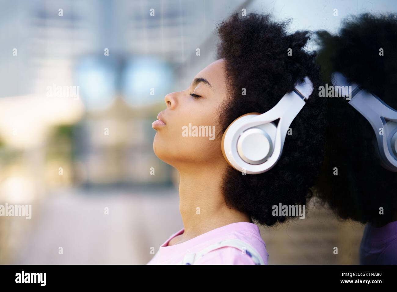 Black woman listening to music on street Stock Photo