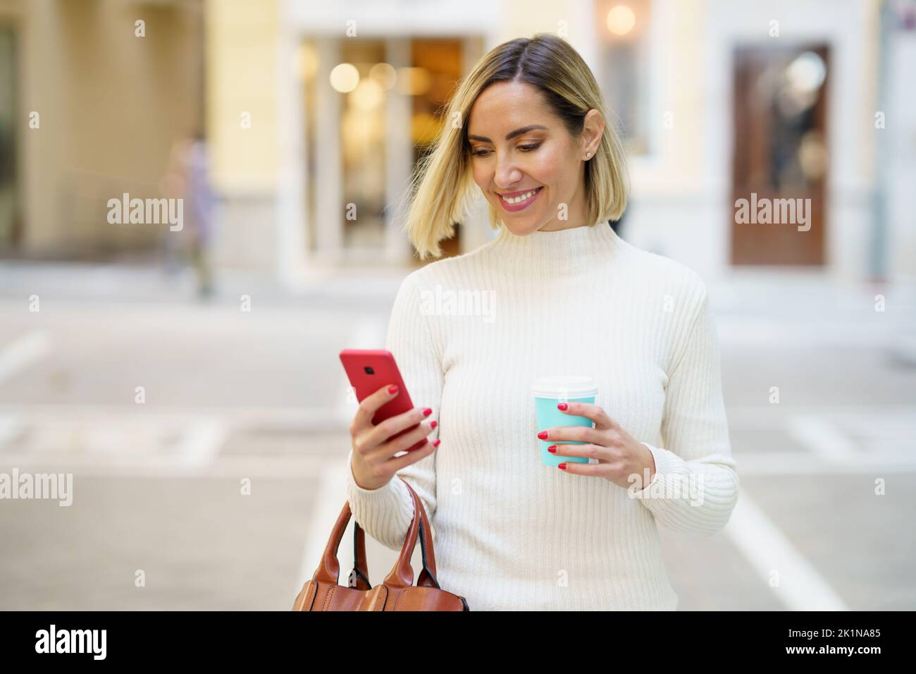 Positive female using smartphone and having coffee Stock Photo