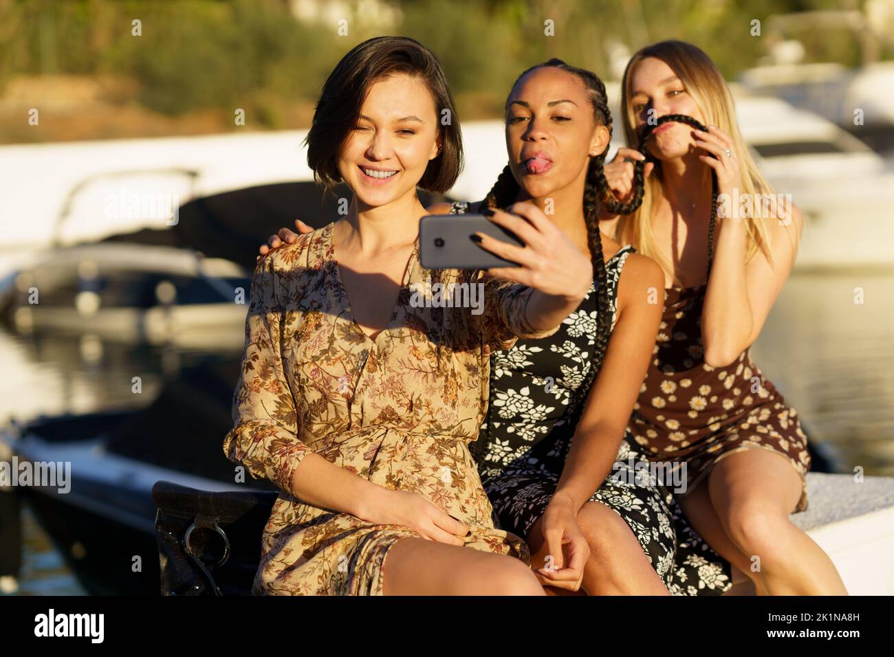 Funny diverse women taking selfie on smartphone on seafront Stock Photo