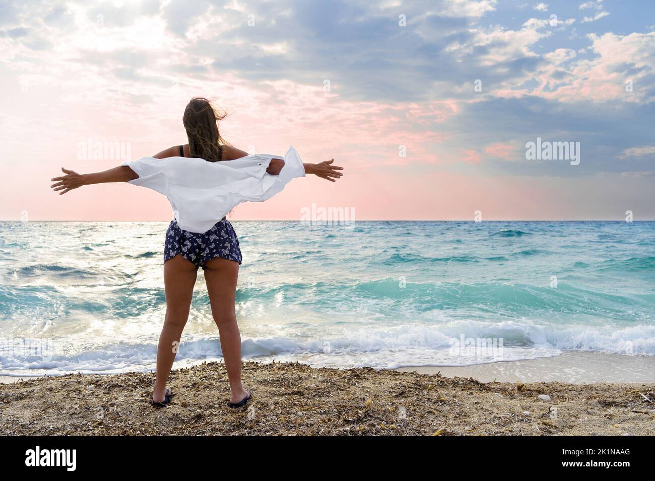 Beautiful woman enjoying her freedom by the sea with arms open Stock Photo