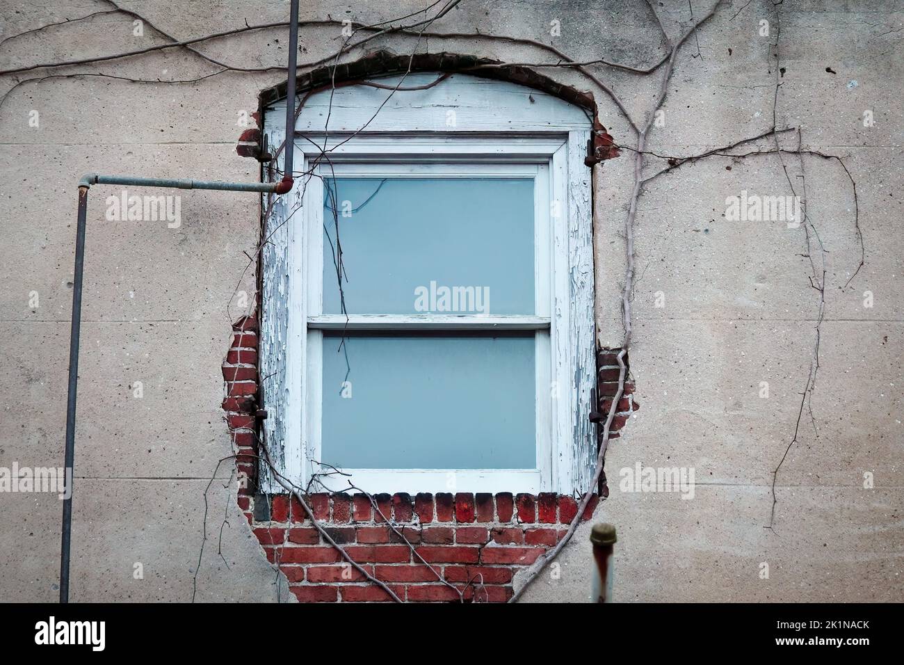 Single urban widow ith peeling paint and exposed conduit. Stock Photo