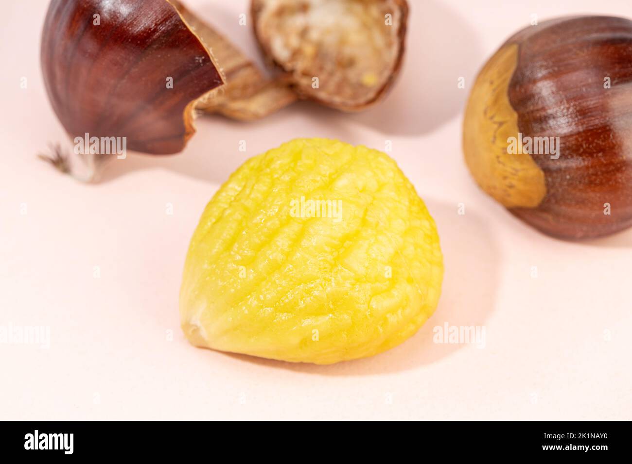 Peeled sweet chestnut on pink background. Castanea sativa Stock Photo