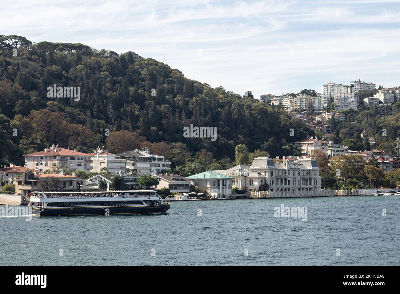 View of a cruise tour yacht on Bosphorus and Bebek neighborhood on European side of Istanbul. It is a sunny summer day. Beautiful travel scene. Stock Photo