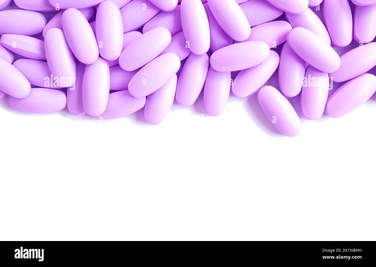 Heap of lavender purple pills on white background with copy space Stock