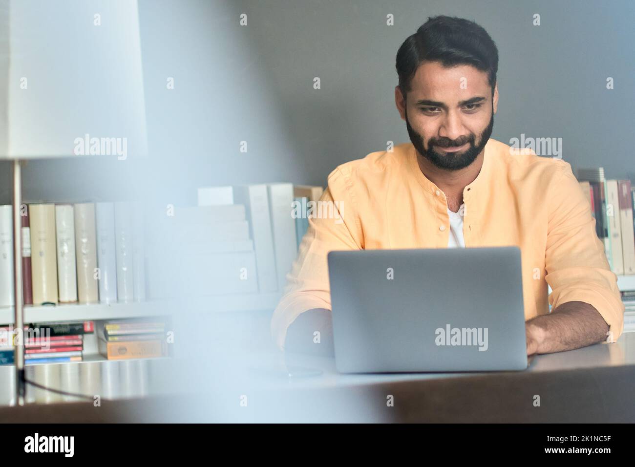 Indian business man using laptop in office thinking on online market analysis. Stock Photo