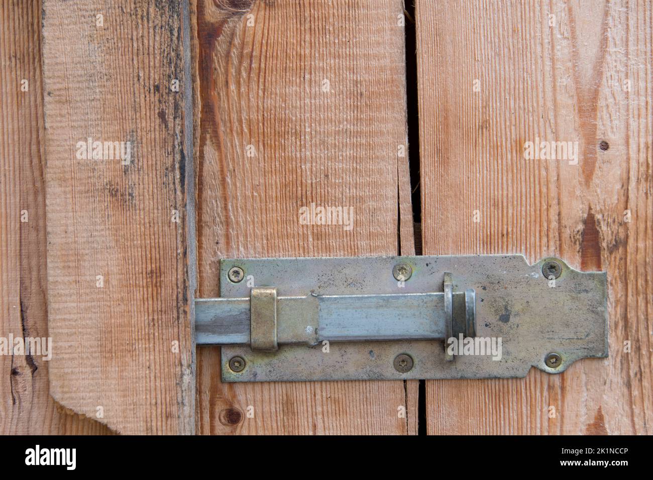 Close up of wooden door made of boards with metal brass iron locking