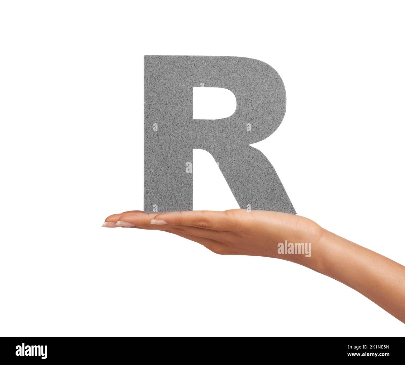 The letter R in her palm. A young woman holding a capital letter R isolated on a white background. Stock Photo