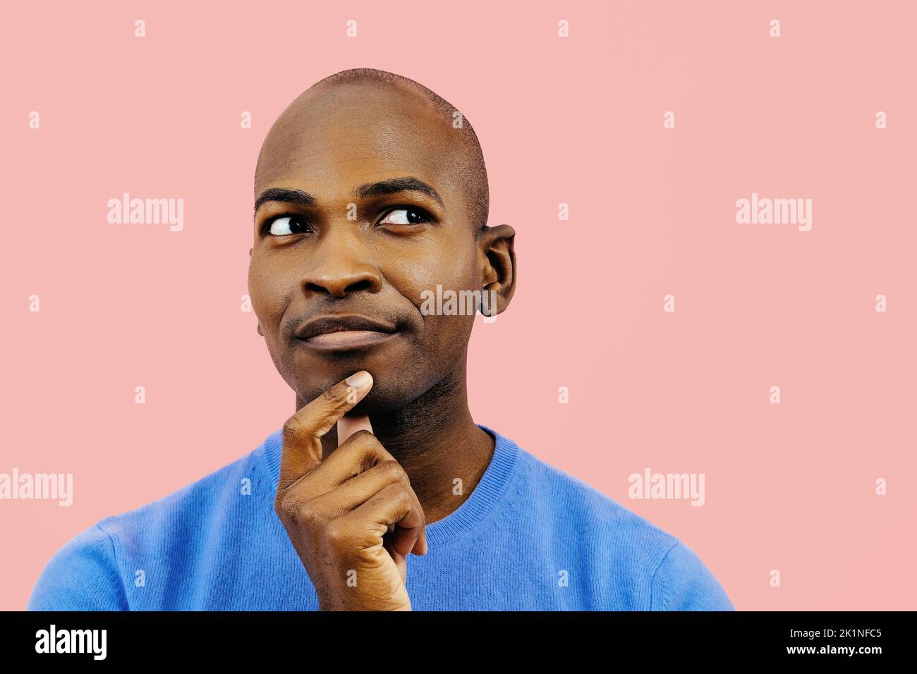 thoughtful man with hand on chin indoors studio looking at copy space headshot Stock Photo