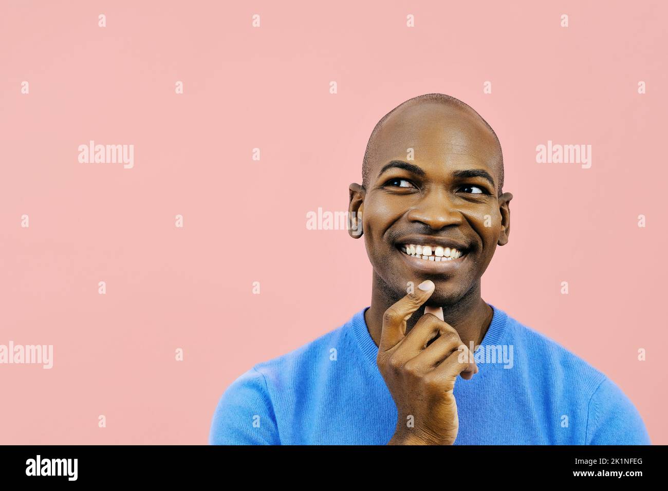 Smiling man with hand on chin indoors studio looking away at copy space close up Stock Photo
