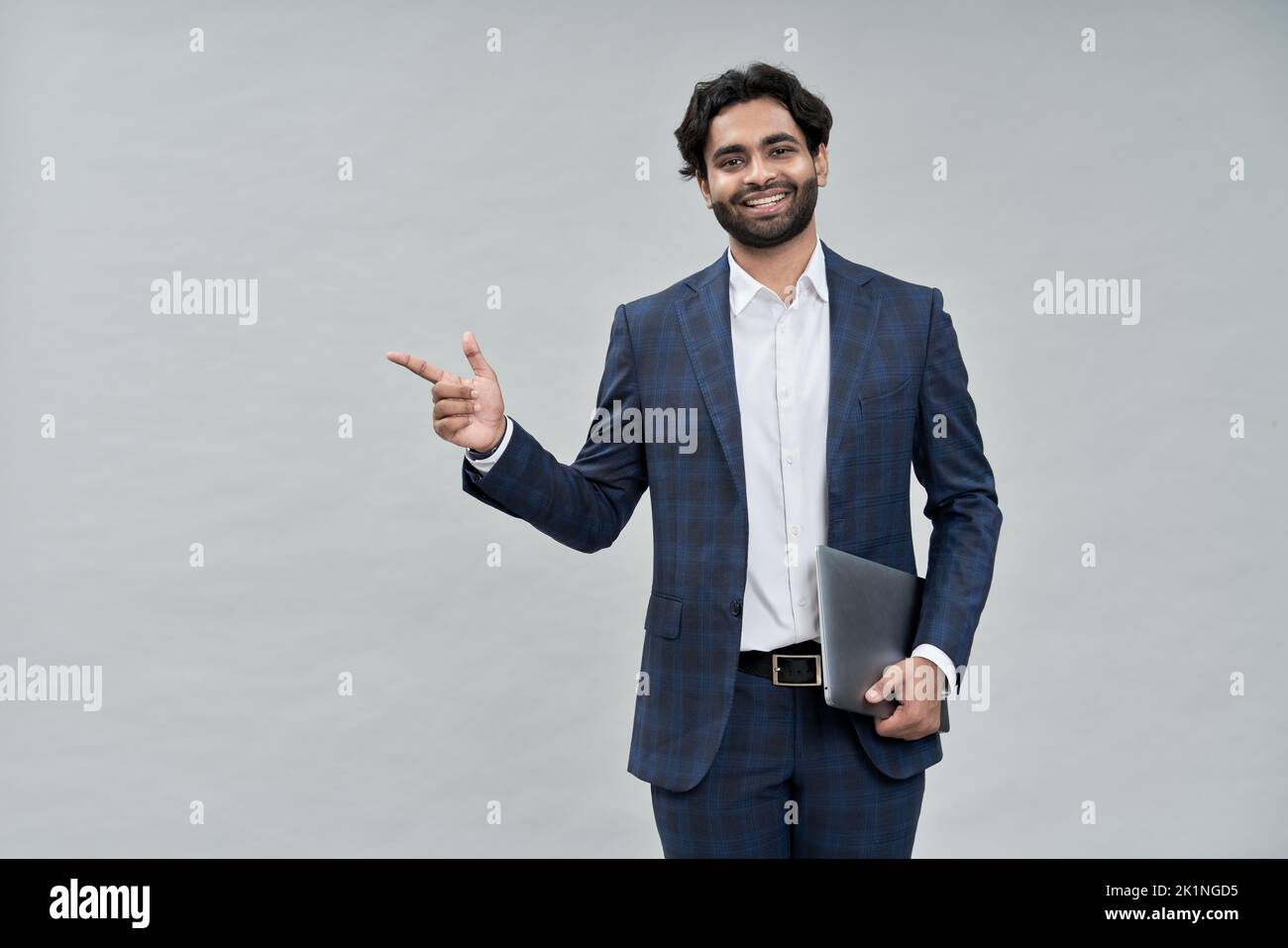 Smiling young indian arab business man wearing suit pointing isolated, portrait. Stock Photo