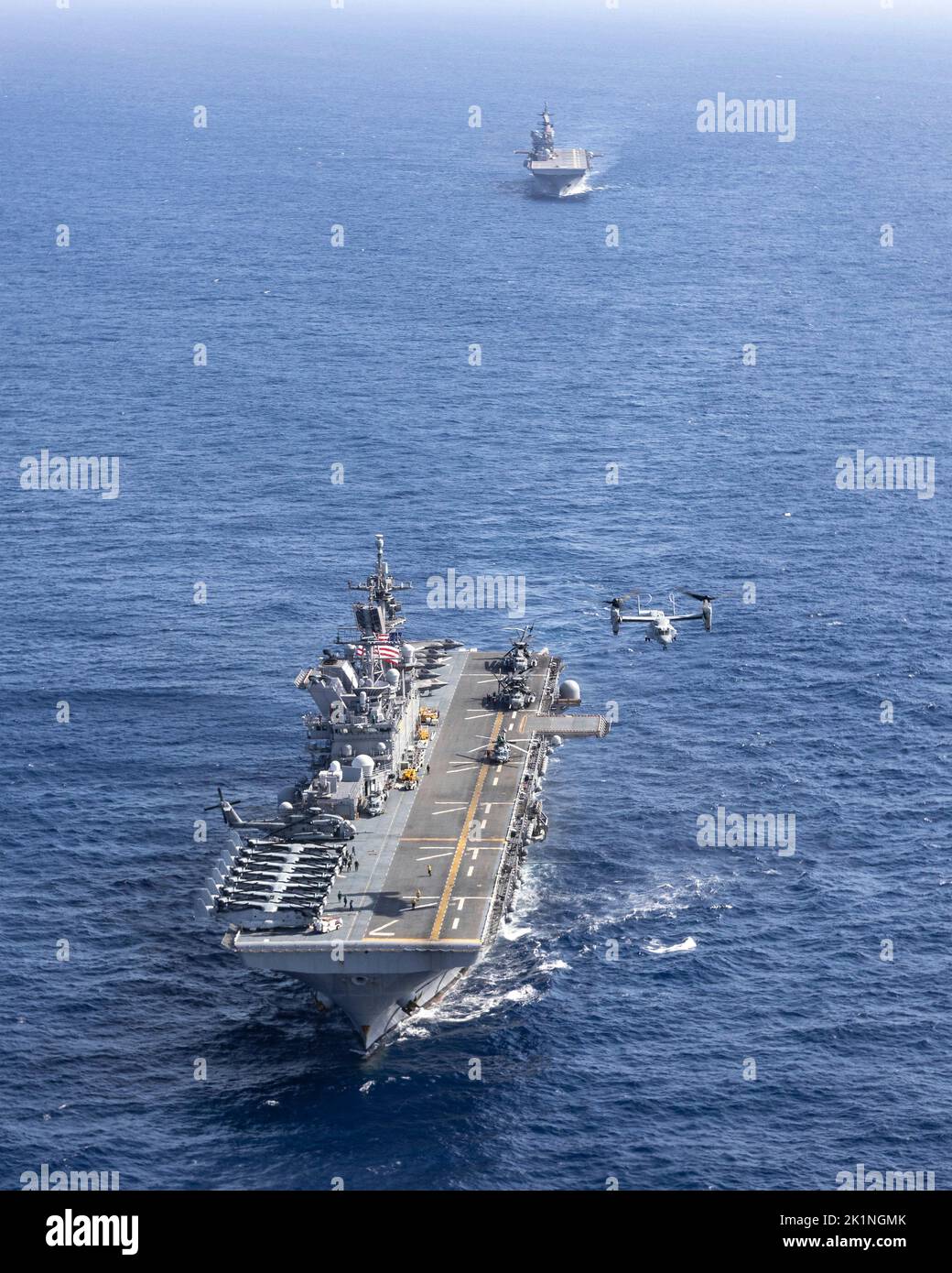 Philippine Sea, United States. 17 September, 2022. A U.S. Marine Corps MV-22B Osprey aircraft takes off from the U.S. Navy America-class amphibious assault ship USS Tripoli, bottom, as it sails with the amphibious assault ship USS America during a training operation, September 17, 2022 in the Philippine Sea. Credit: LCpl. Christopher Lape/U.S. Marines Photo/Alamy Live News Stock Photo