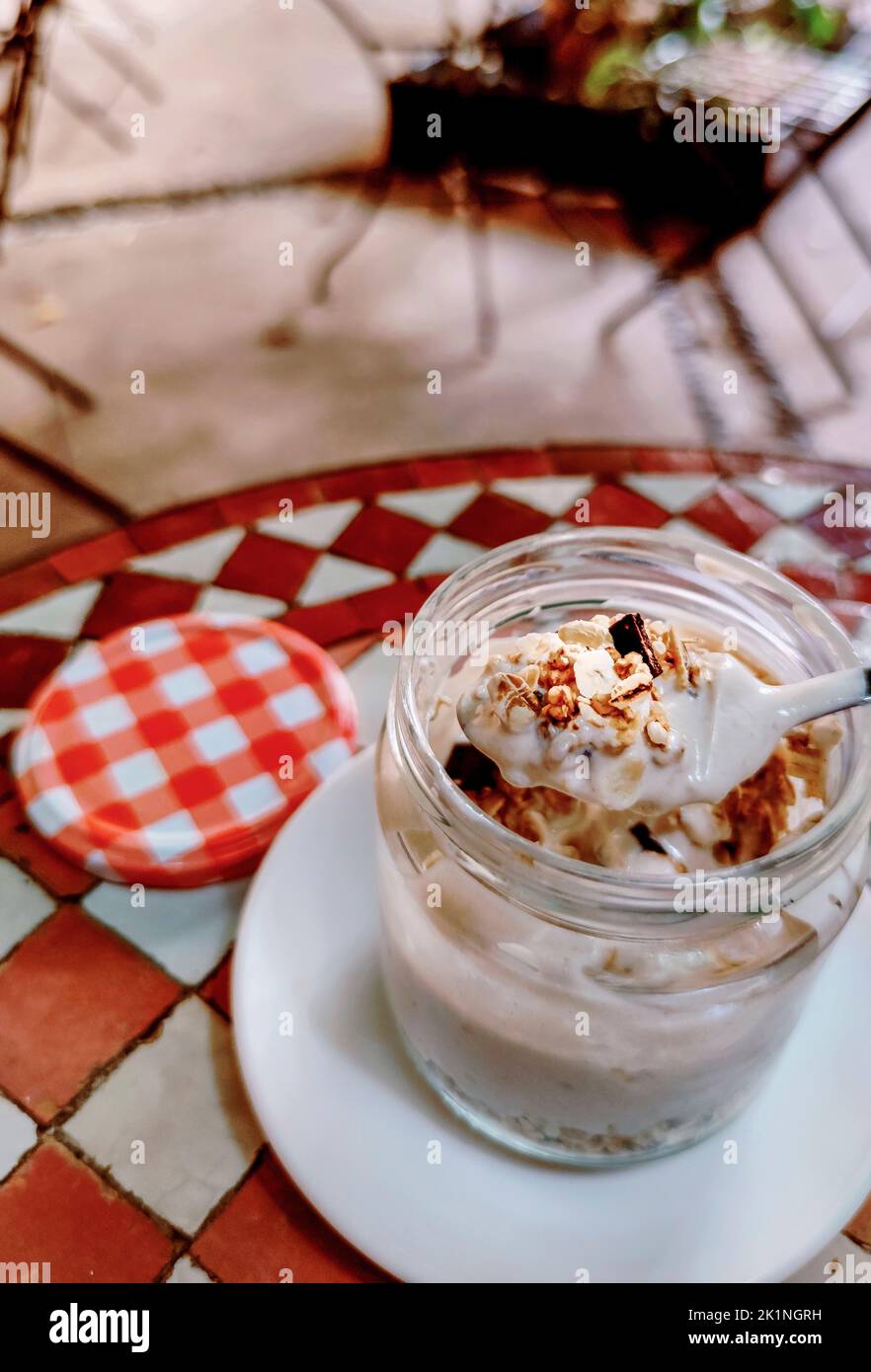 Spoonful of yogurt with muesli from glass jar. Mediterranean style background Stock Photo