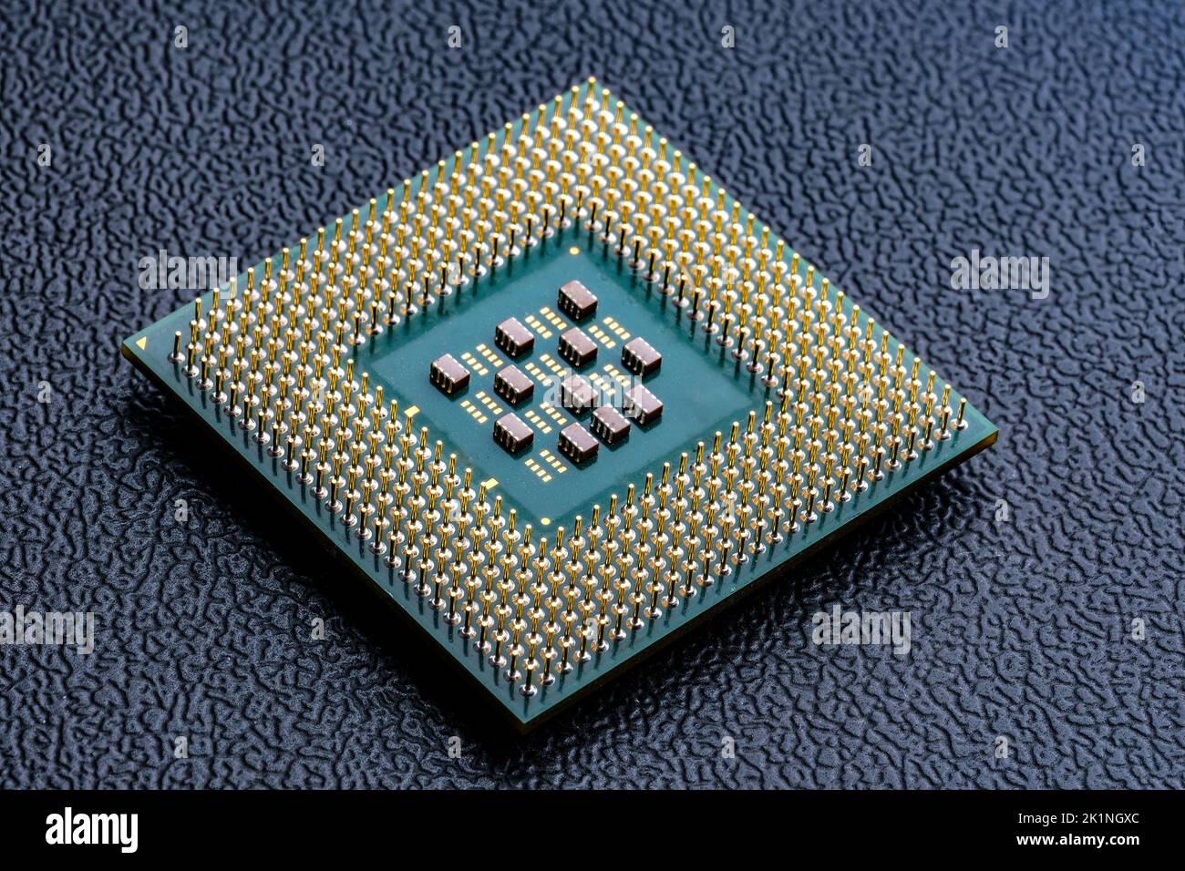 Large computer chip CPU with hundreds of gold pins and tiny components - capacitors, resistors on its board. Concept for microchips and semiconductor Stock Photo
