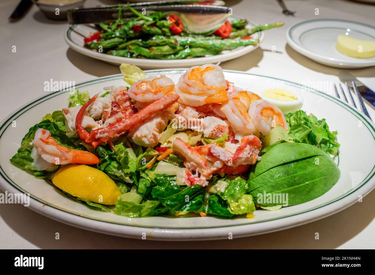 selective focus on seafood salad plate with crab, shrimp and lobster as well as avocado and lemon wedge Stock Photo