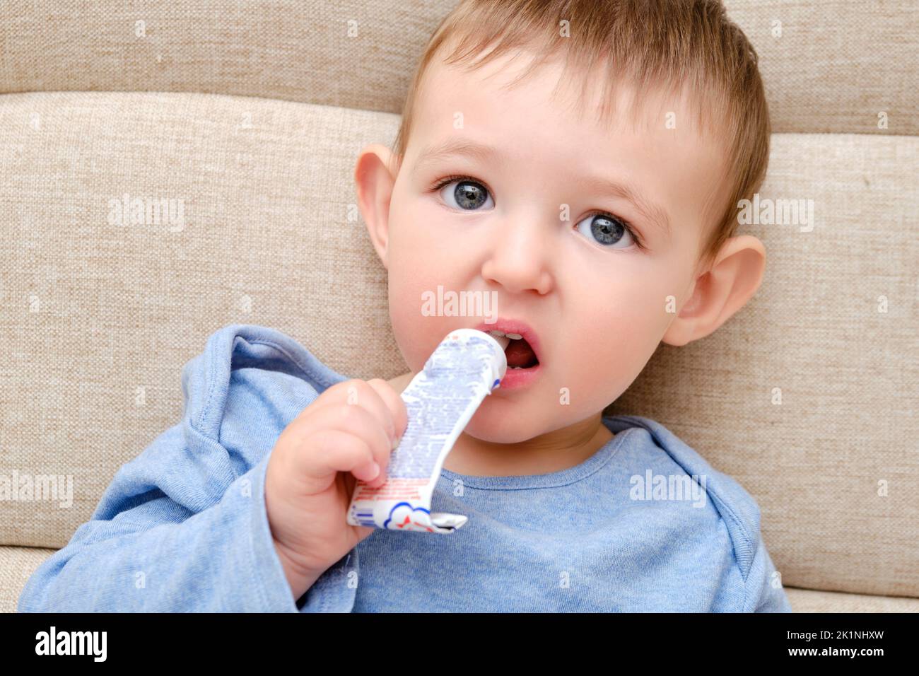 Child puts a tube of medicine into his mouth. Toddler baby aged one