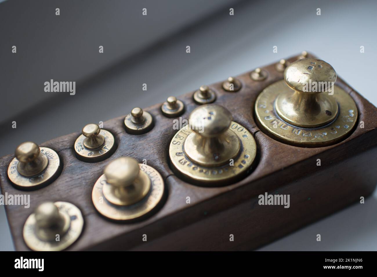 Set of golden traditional weights in a wooden box seen from above Stock Photo
