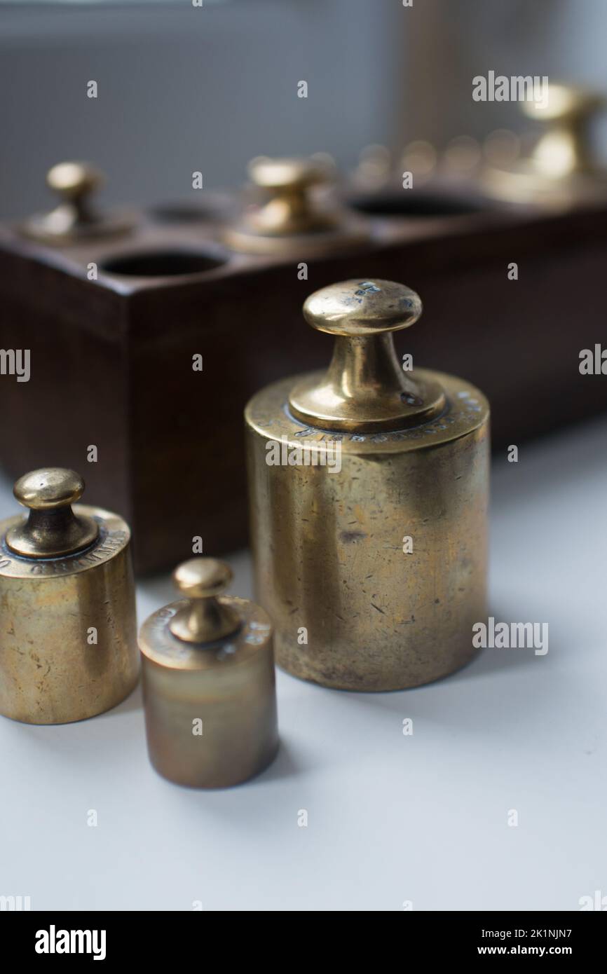 Three golden units of weight. Set in a wooden box in the background Stock Photo