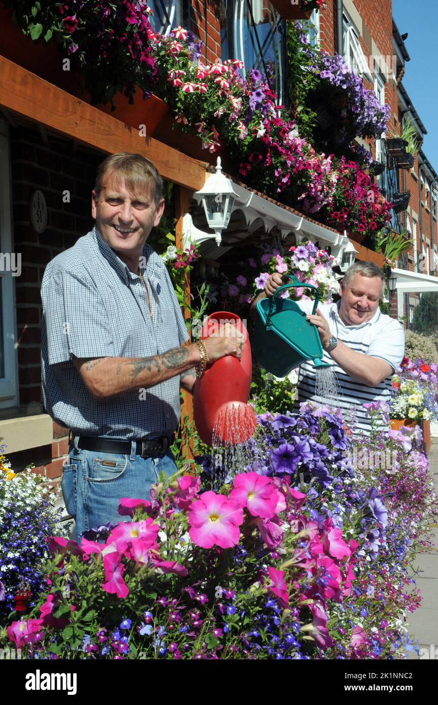 Neighbours Philip Whicker, left,  and Les Carstairs have turned their tiny inner-city front gardens into a blooming tourist attraction.  The green-fingered pair even overcame the initial opposition of a housing association who own their homes by transforming their street-side facades into a huge flash of bright colours, upstairs and downstairs.   Bus driver Les, 53, and next-door pal Philip, 56, came up smelling of roses after deciding on a way to brighten up their three-storey town houses in Portsmouth,  and at minimum cost.  Philip, a ferry hand, said:’’ We only have small front gardens. Min Stock Photo