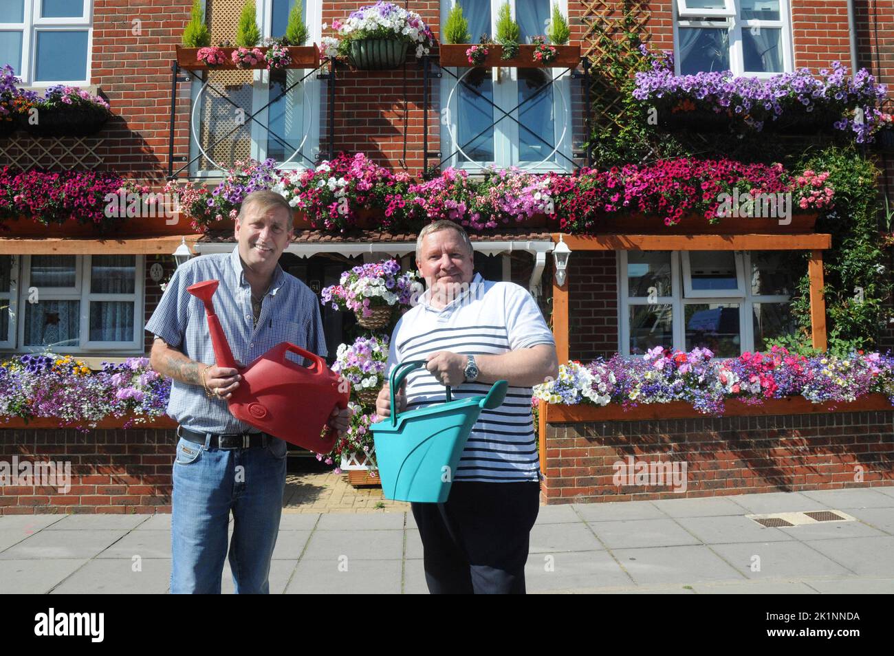 Neighbours Philip Whicker, left,  and Les Carstairs have turned their tiny inner-city front gardens into a blooming tourist attraction.  The green-fingered pair even overcame the initial opposition of a housing association who own their homes by transforming their street-side facades into a huge flash of bright colours, upstairs and downstairs.   Bus driver Les, 53, and next-door pal Philip, 56, came up smelling of roses after deciding on a way to brighten up their three-storey town houses in Portsmouth,  and at minimum cost.  Philip, a ferry hand, said:’’ We only have small front gardens. Min Stock Photo