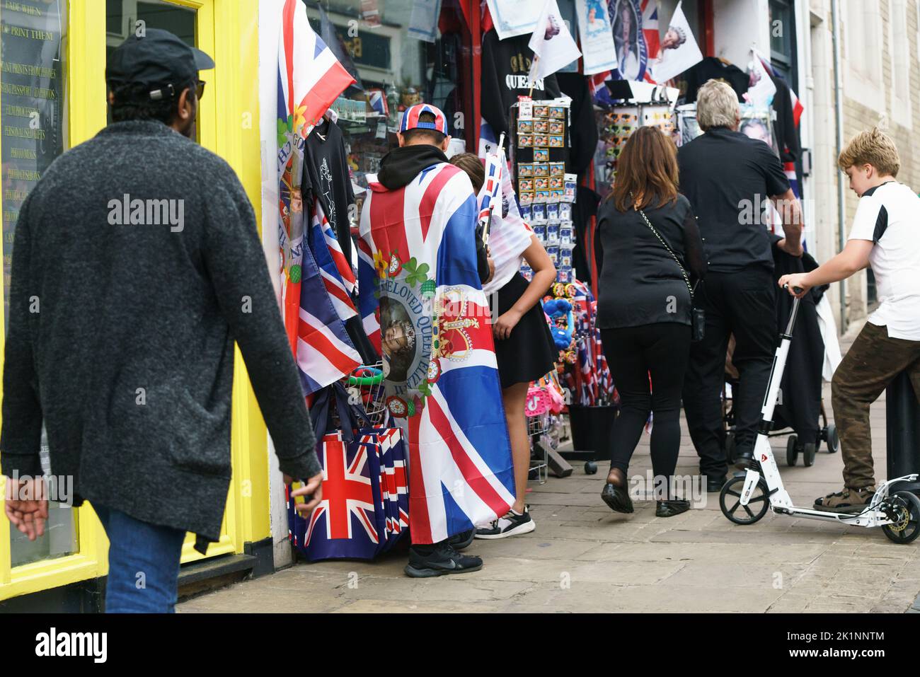 A man dressed in a union jack flag outside of a store selling royal memorabilia, Windsor, UK prior to the receiving of the late queen and hearse. Stock Photo
