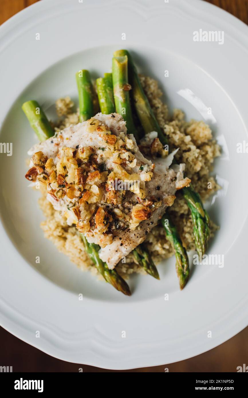 serving of Trout amandine with bulgur wheat and asparagus in white bowl Stock Photo