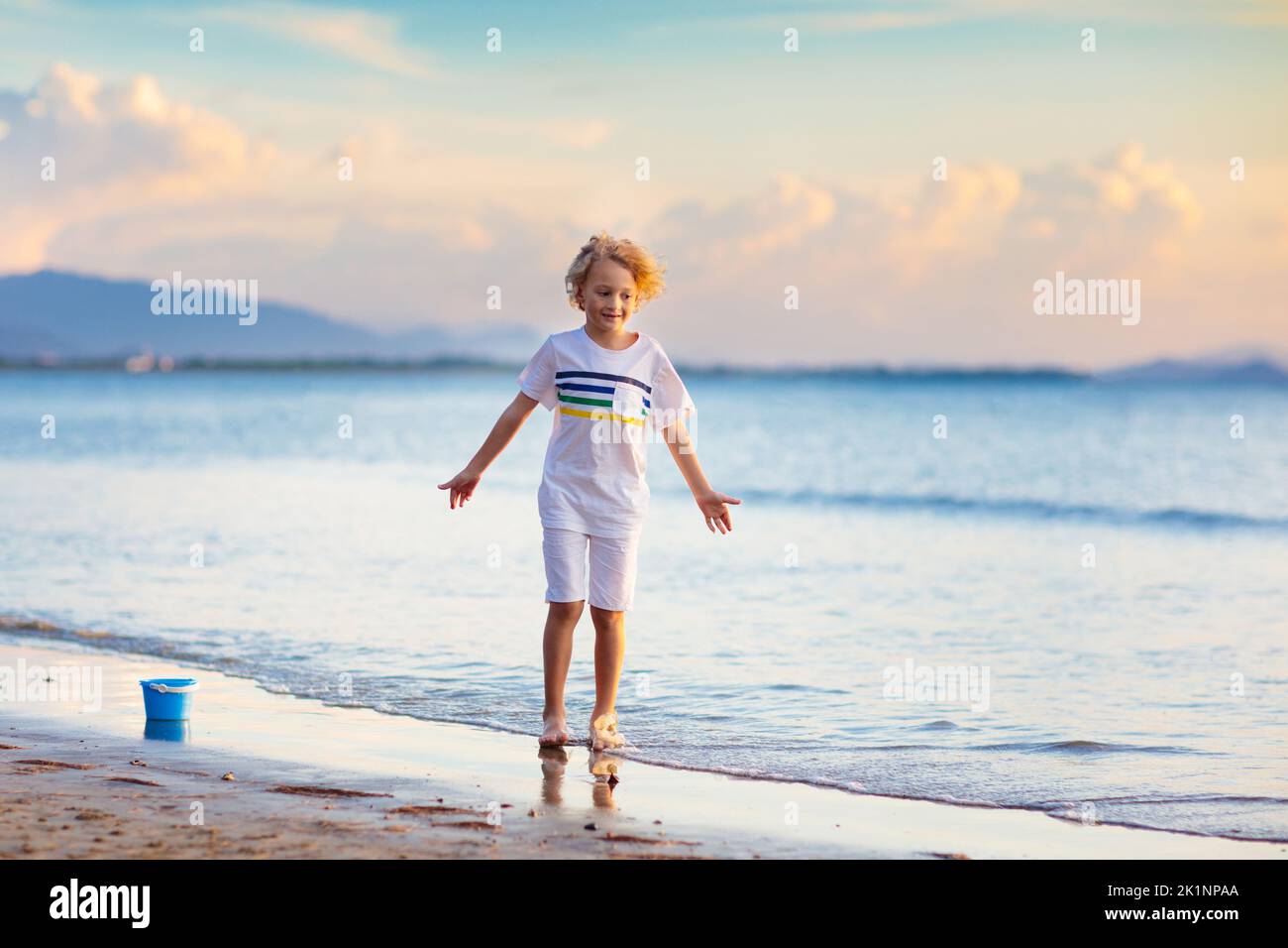 Child playing on tropical beach. Little boy at sea shore. Family summer vacation. Kids play with water and sand toys. Ocean and island fun. Travel wit Stock Photo