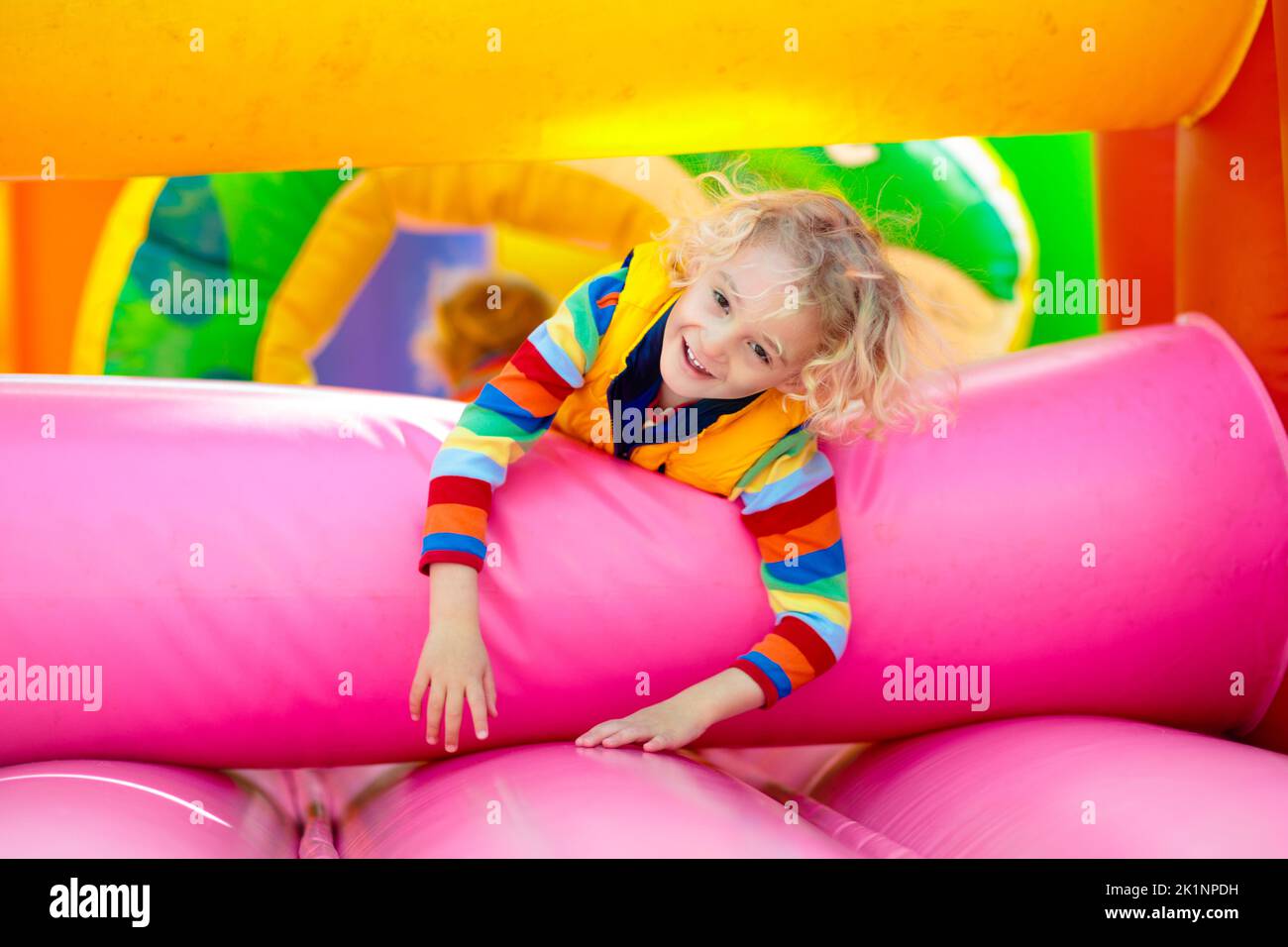 Child jumping on colorful playground trampoline. Kids jump in inflatable bounce castle on kindergarten birthday party Activity and play center for you Stock Photo