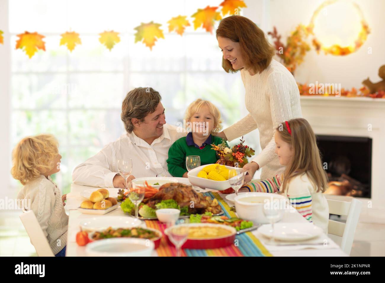 Family with kids eating Thanksgiving dinner. Roasted turkey and pumpkin pie on dining table with autumn decoration. Parents and children having festiv Stock Photo
