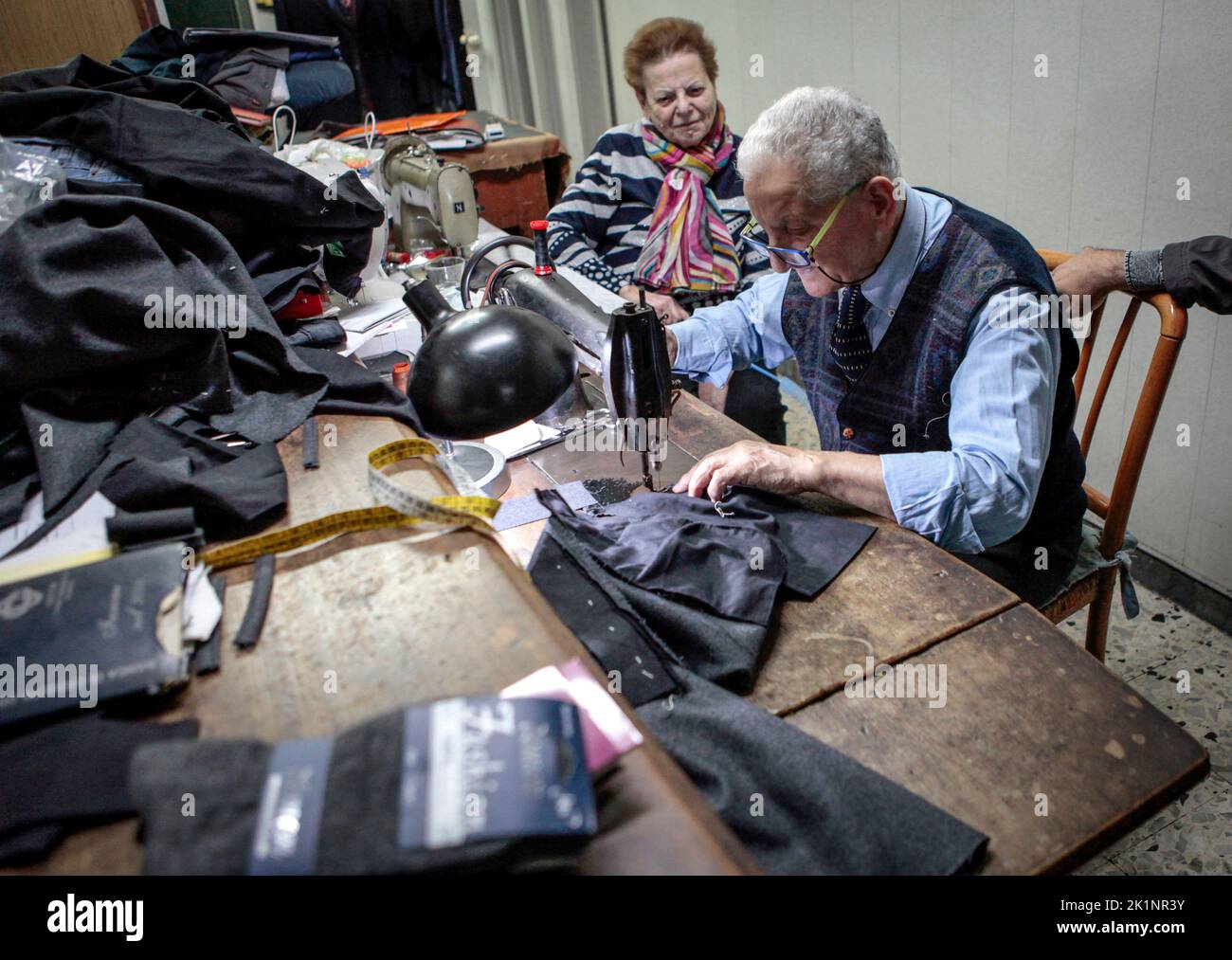 an elderly tailor working and sewing in his small shop in town of Scafati, region of Naples, near Pompeii ,Italy Stock Photo