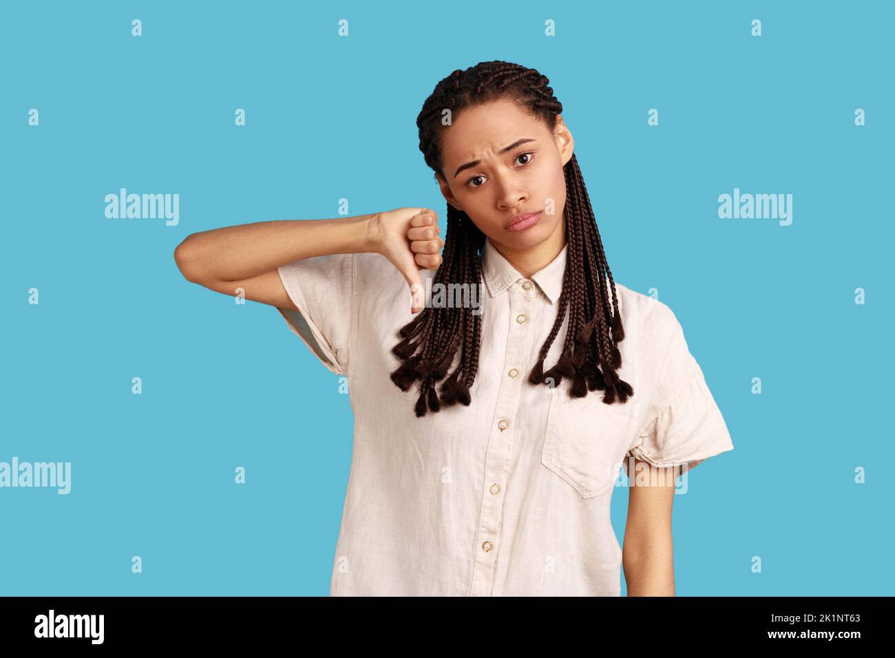 Discontent woman with black dreadlocks showing disapproval sign, keeps ...